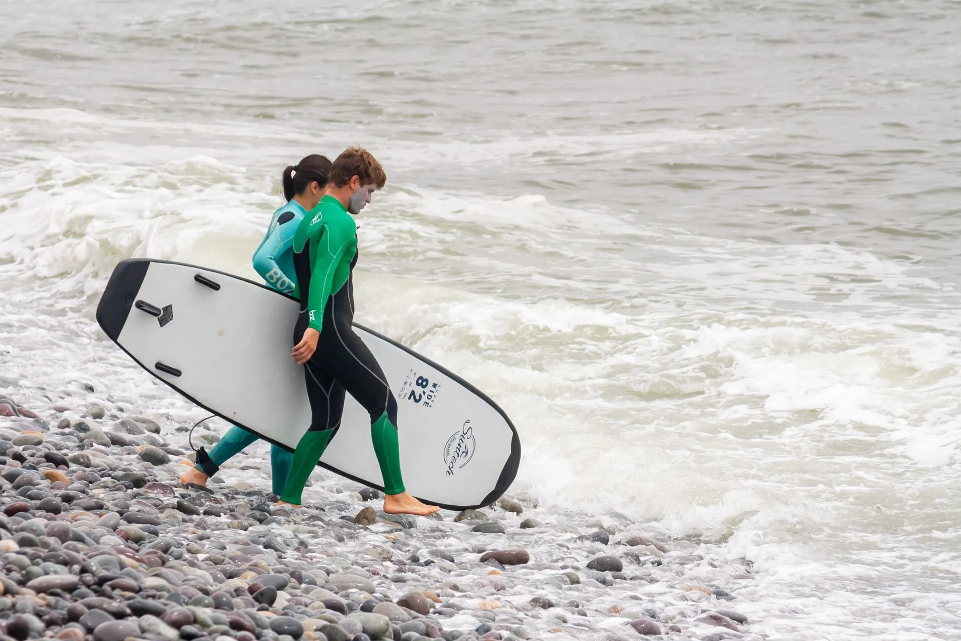 Beginner surfer riding a small wave at Makaha Beach below the Miraflores cliffs in Lima, Peru