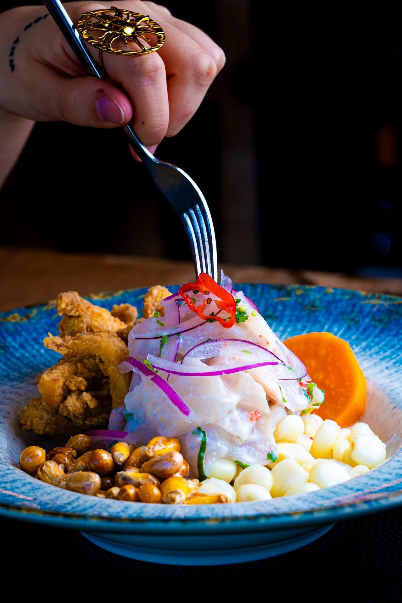 A colorful plate of Peruvian ceviche garnished with fried seafood and corn